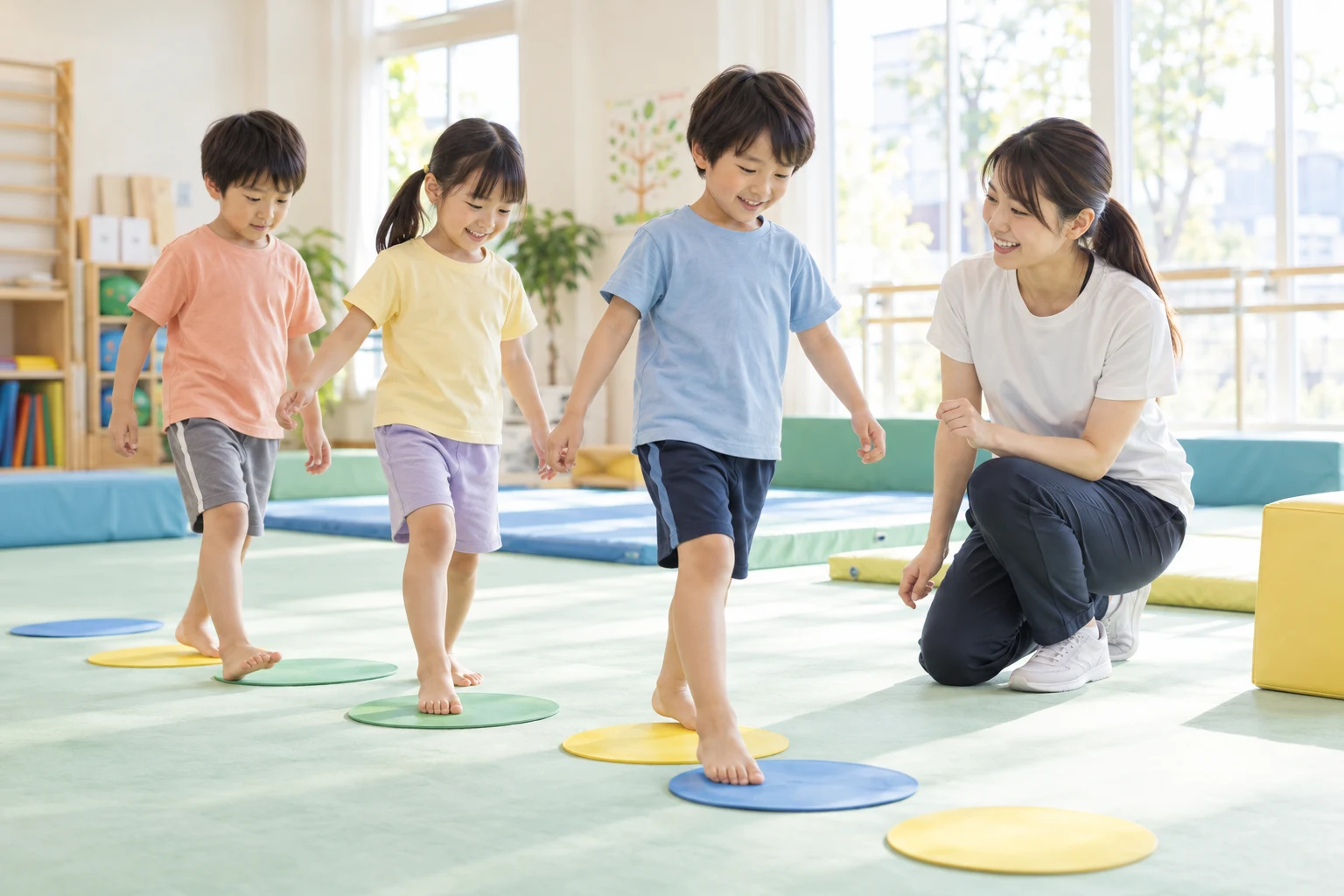 明るい体育室で、コーチと一緒に体を動かす子どもたちのレッスンイメージ